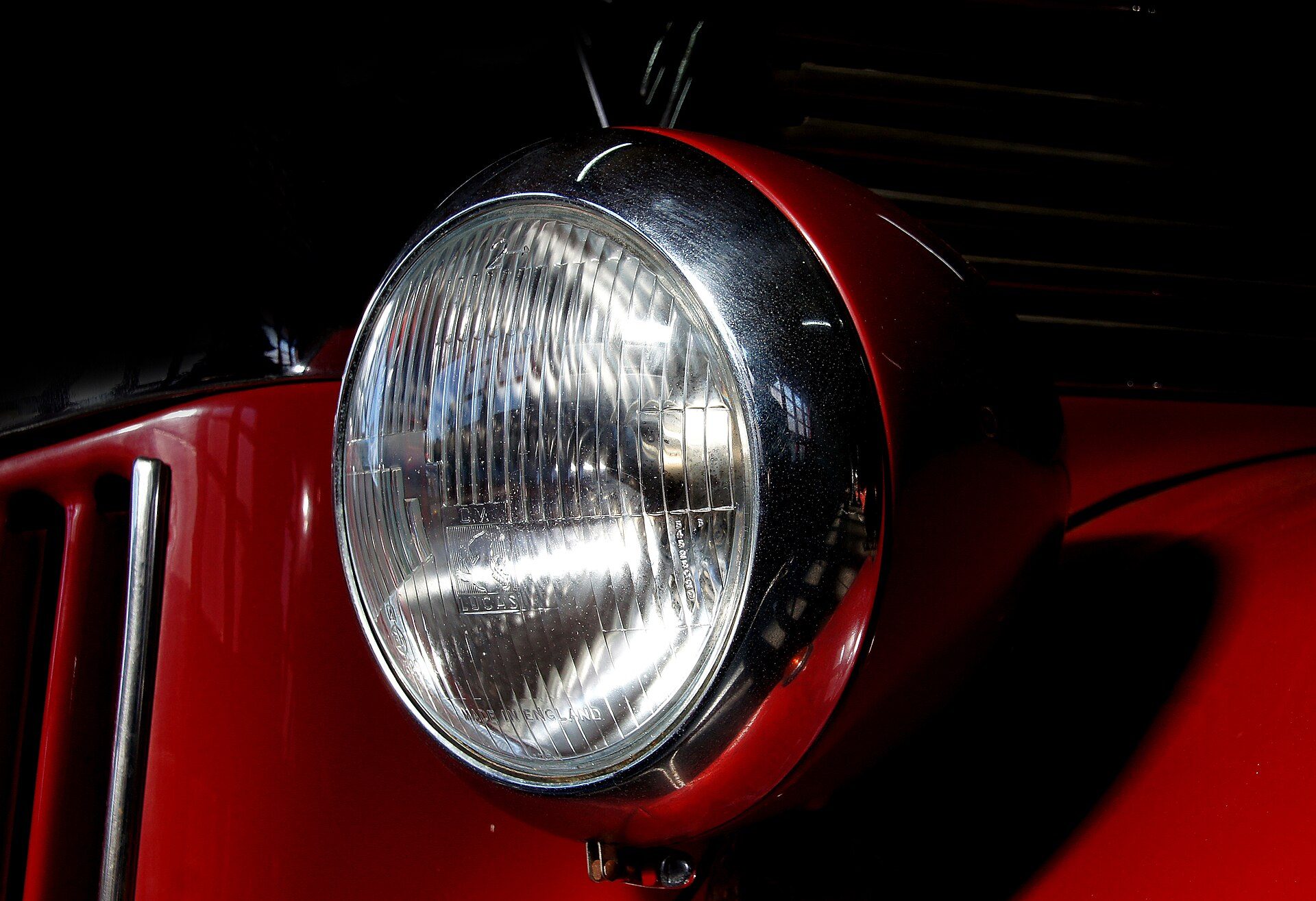 Chrome headlight on a red classic car