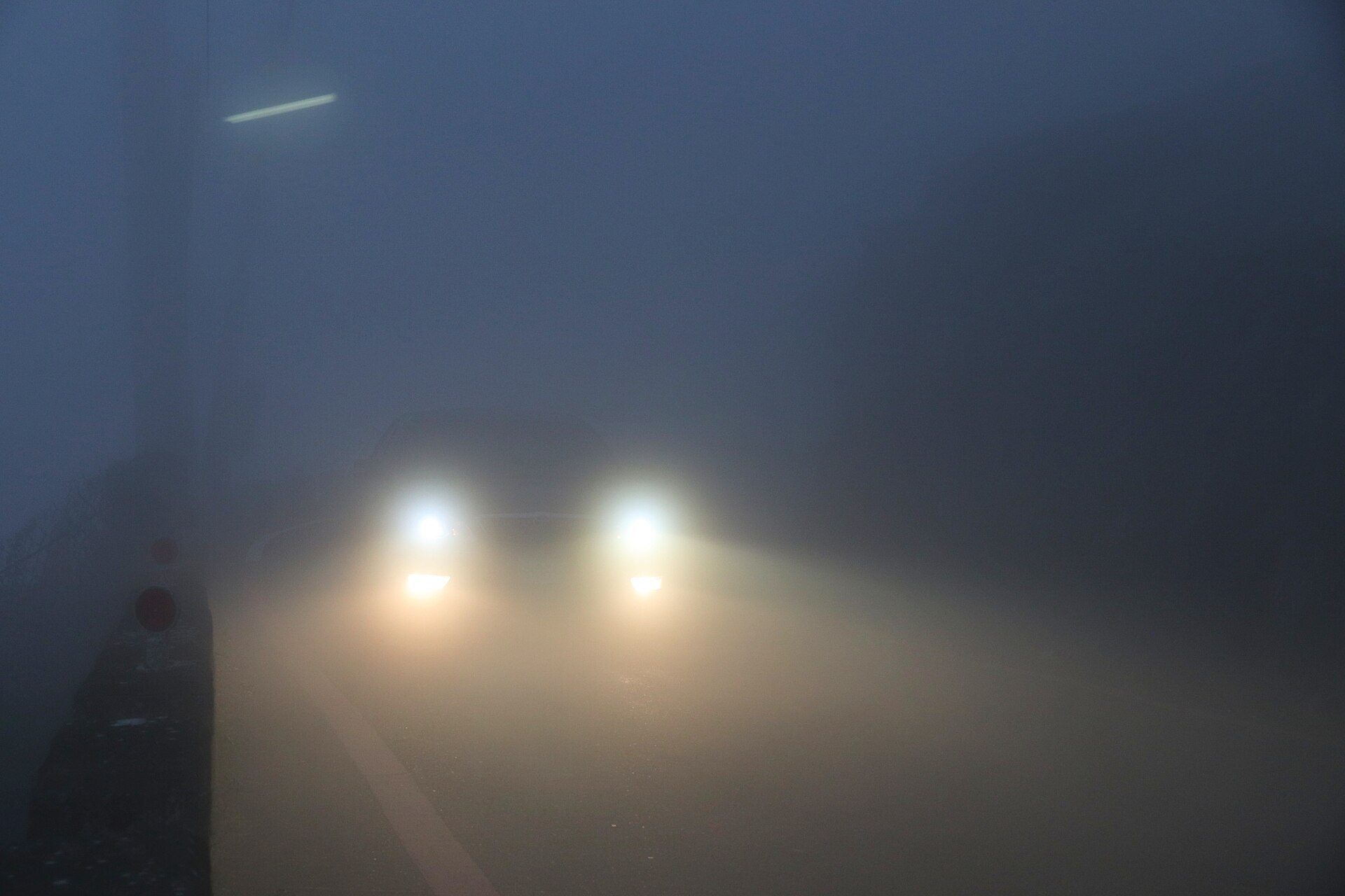 Headlights glowing through dense fog
