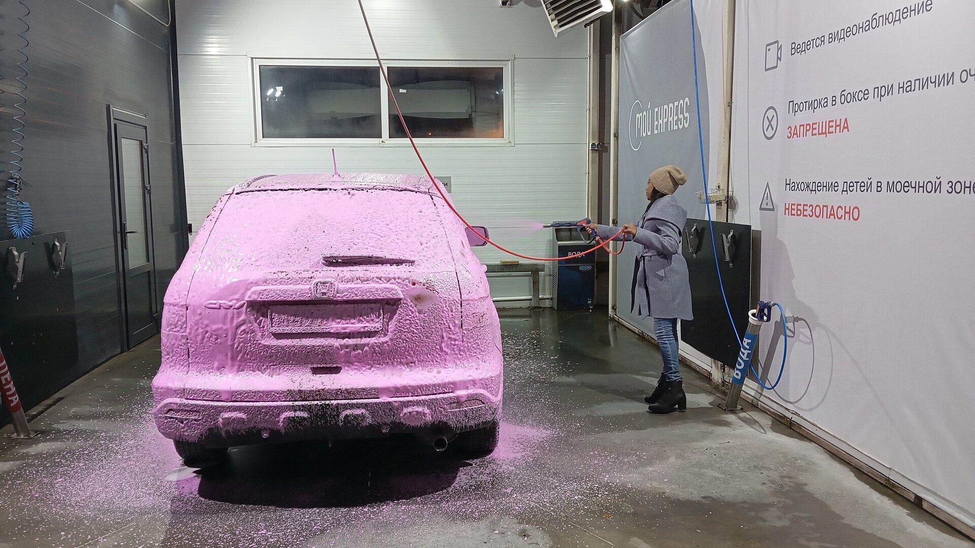 Car covered in pink foam at a wash bay